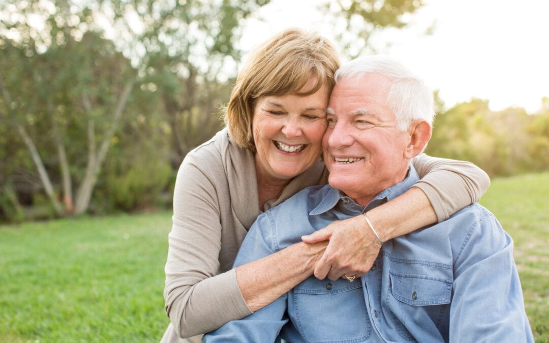 elderly couple hugging and smiling in park