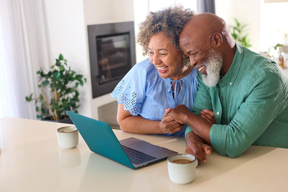 Happy black couple smiling and typing on a computer